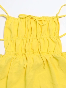 Detail of yellow backless dress featuring tiered smocking and adjustable bow straps