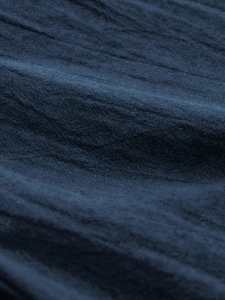 Close-up of navy blue linen fabric with natural wrinkled texture and breathable weave
