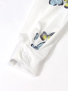 Macro detail of butterfly print on lightweight white blouse with buttoned cuff