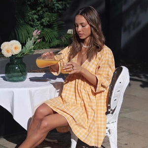 Détail d'une robe vichy jaune à col en V et manches bouffantes dans un jardin ensoleillé