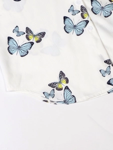 Detail of white butterfly print blouse featuring blue and yellow motifs with pearl buttons