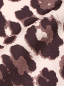 Detailed close-up of leopard print fabric with pink base and twill texture on shirt