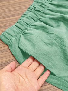 Detail of green elastic waist cropped pants showing side pocket and fabric texture