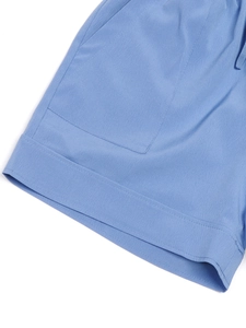 Vue détaillée du short bleu clair montrant la texture du tissu et la couture de la poche