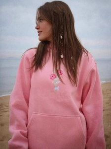 Pink oversized hoodie with poppy flower embroidery on a soft beach background