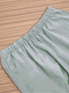 Detail of high waisted elastic waistband on sage green textured cropped pants for women