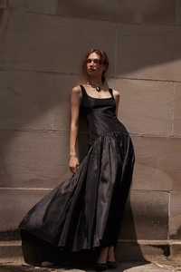 Détail de la robe longue noire élégante avec jupe plissée volumineuse et finition satinée