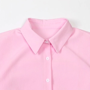 Detail view of pink cotton linen suit jacket collar and white resin button closure