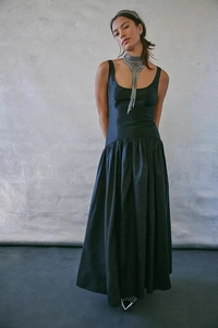 Détail d'une robe longue noire sans manches avec couture haute et jupe à plis sophistiqués