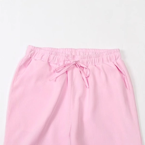Detail of light pink linen pants showing elastic waist with drawstring and soft fabric