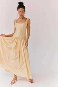 Détail d'une robe longue en satin champagne avec jupe plissée fluide et taille haute élégante