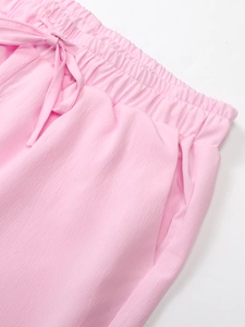 Detail of pink cotton linen pants with elastic waist, drawstring bow, and side pockets