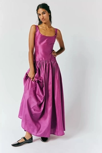 Détail d'une robe longue en satin fuchsia avec col carré et ourlet plissé fluide