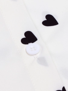 Close-up of white heart print shirt showing delicate fabric texture and white button