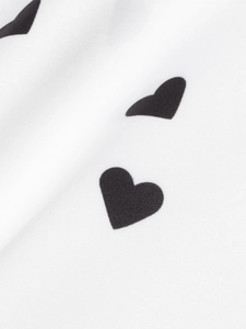 Detail shot of the high-quality white fabric with black heart print on a women's shirt