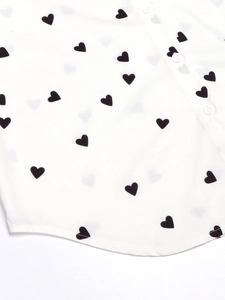 Detail of white heart print shirt showing smooth fabric and button closure with curved hem