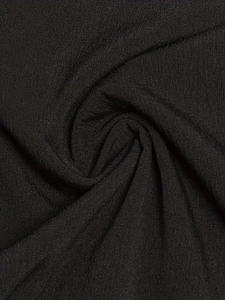 Close-up of black knit fabric showing the fine texture and soft drape of casual pants