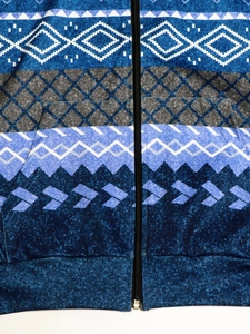 Detail of zip-up hoodie featuring geometric ethnic prints and metallic zipper closure