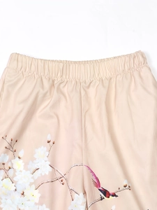 Détail de la taille élastique du pantalon beige avec motifs de fleurs et d'oiseaux