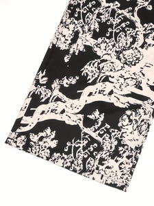 Detailopname van witte bloemenprint en zoomstiksels op zwarte katoen-linnen broek