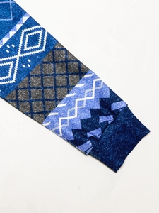 Detail of blue geometric patchwork sleeve with rib-knit cuff and rhombus pattern