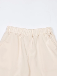 Detail of beige cotton linen trousers featuring elastic waistband and side pockets