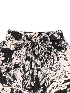Detailweergave van damesbroek met bloemenprint, elastische hoge taille en een strikceintuur