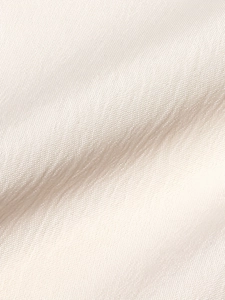 Close-up of lightweight light beige cotton linen fabric texture with a soft draping effect