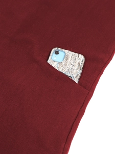 Detail of a burgundy cotton linen dress showing a large practical side pocket with a phone