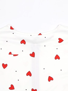Detail des weißen Langarmoberteils mit roten Herzmustern und schwarzen Polka-Dots-Stoff