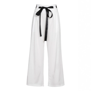 Detail of high-waisted white wide-leg trousers featuring a stylish black satin bow belt