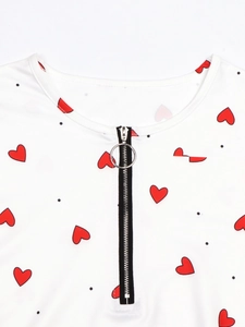 Detail eines weißen Poloshirts mit Herzprint und silbernem Ring-Reißverschluss