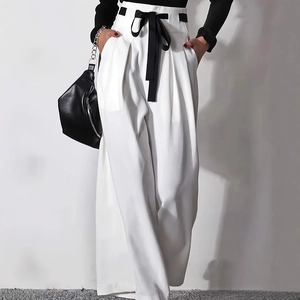 Detail of high-waisted white wide-leg trousers featuring a stylish black lace-up bow belt