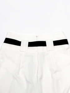 Detail of white trousers featuring a wide black ribbon belt and invisible back zipper