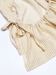 Close-up of yellow and white striped top featuring side ties and textured cotton fabric