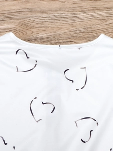 Detail des weißen Polo-Ausschnitts mit schwarzem Herzprint und glatten Nähten