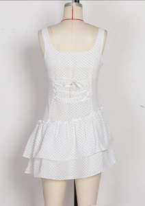 Detail view of the back of a white polka dot mini dress with criss-cross lace-up straps