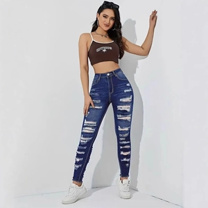 Detail of high waist skinny jeans featuring distressed ripped holes and raw edge hems