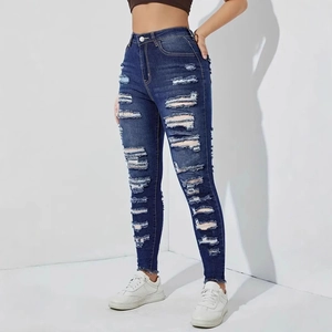 Close-up of distressed denim jeans with large ripped holes and frayed hems on high-waist fit