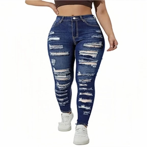 Detail of high-waist ripped blue denim jeans showing frayed holes and distressed texture