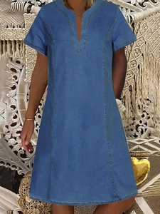Dettaglio dello scollo a V e cuciture arancioni a contrasto su abito denim blu medio