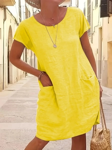 Detail of loose yellow cotton linen dress with practical side pockets and crew neck