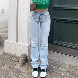 Detail of high-waisted light blue straight jeans with vintage wash and structured denim fabric
