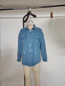 Detailed view of the frayed edges and metal buttons on a light blue denim shirt