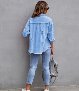 Rear view of light blue denim shirt with distressed holes and frayed raw hem detail