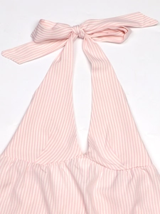 Detail of pink and white striped halter top featuring a decorative bow knot on woven fabric
