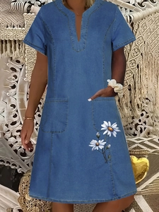 Detail of V-neck denim dress featuring dual front pockets and white daisy print detail