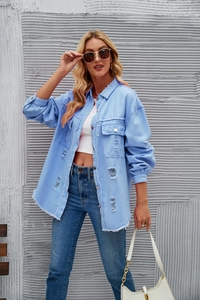 Detail of light blue distressed denim shirt with frayed edges and ripped texture