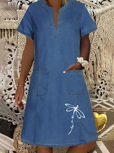 Close-up of V-neck denim dress featuring dragonfly print and functional large pockets