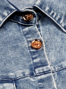 Detail of blue denim dress featuring marble texture buttons and washed twill fabric